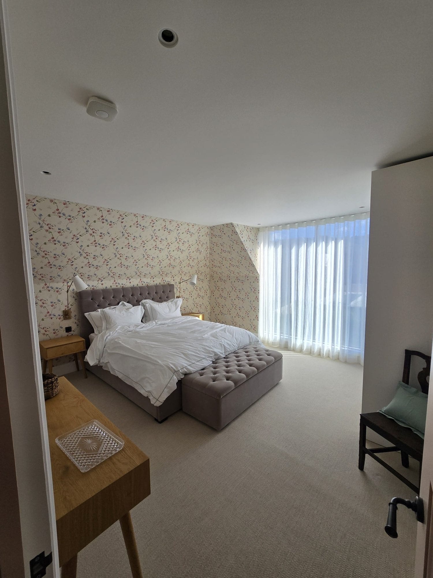Bedroom finished with floral wallpaper and soft natural light.