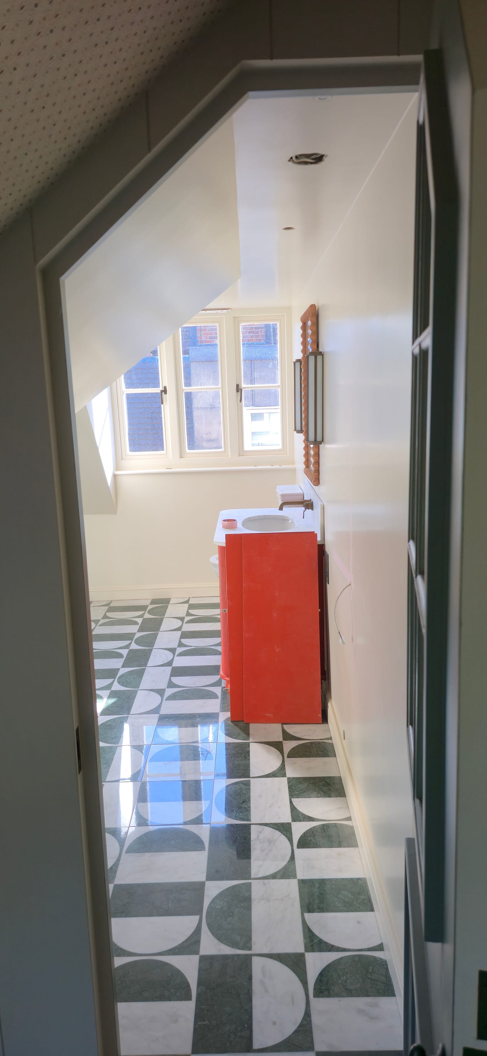 Top-floor ensuite with geometric floor tiles, coral vanity, white walls, and glass shower.