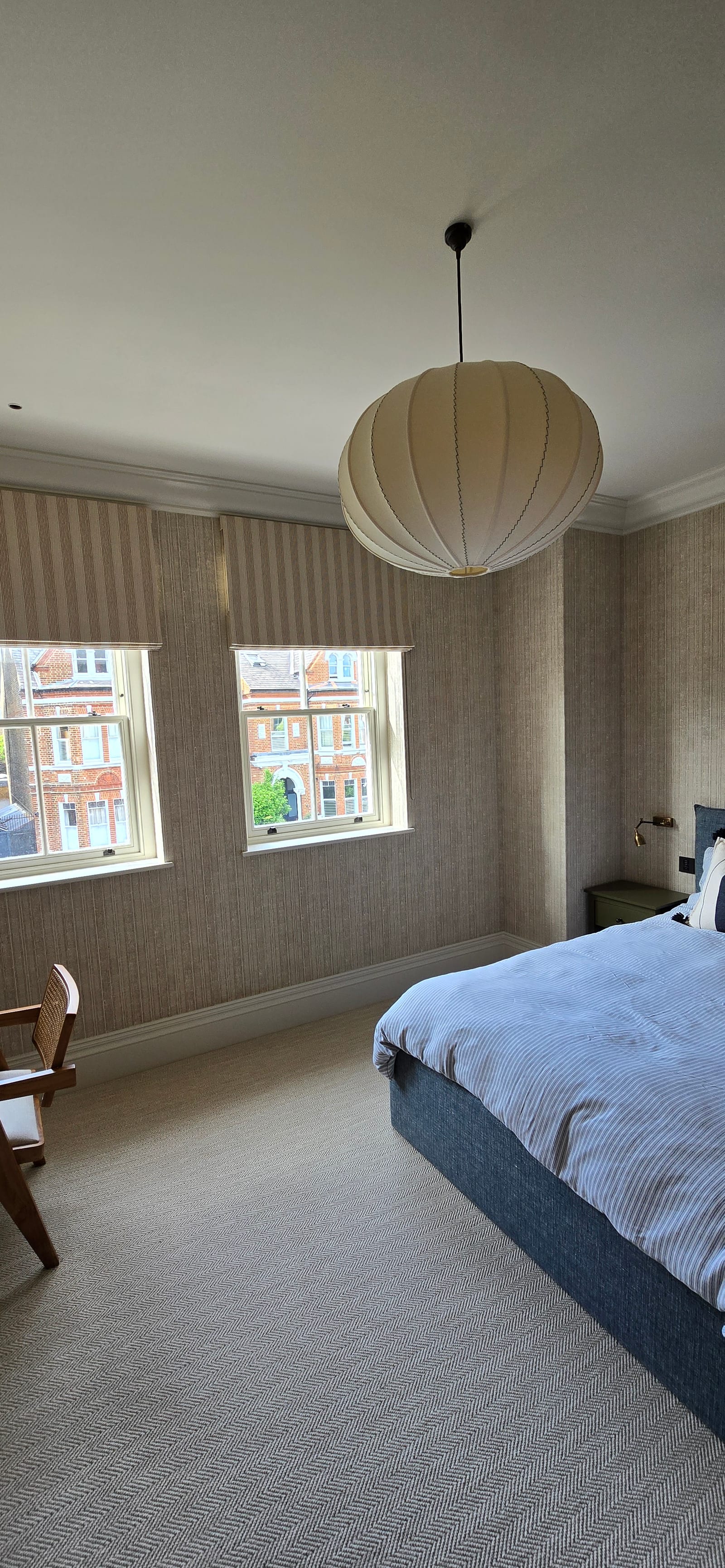 Bedroom finished with soft textured grasscloth walls, dual sash windows, and painted trim.