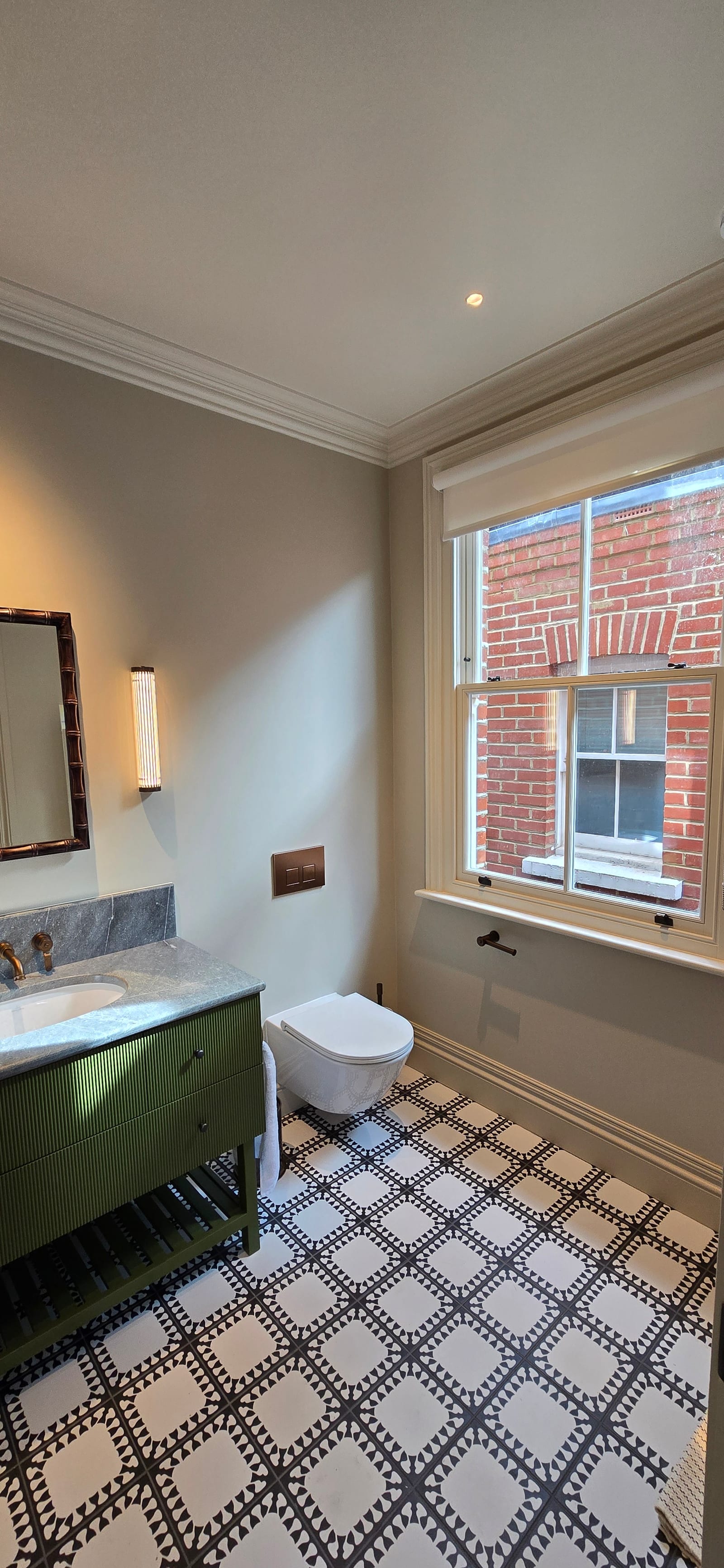 Ensuite bathroom with olive fluted vanity, stone top, brass taps, and geometric floor tiles.