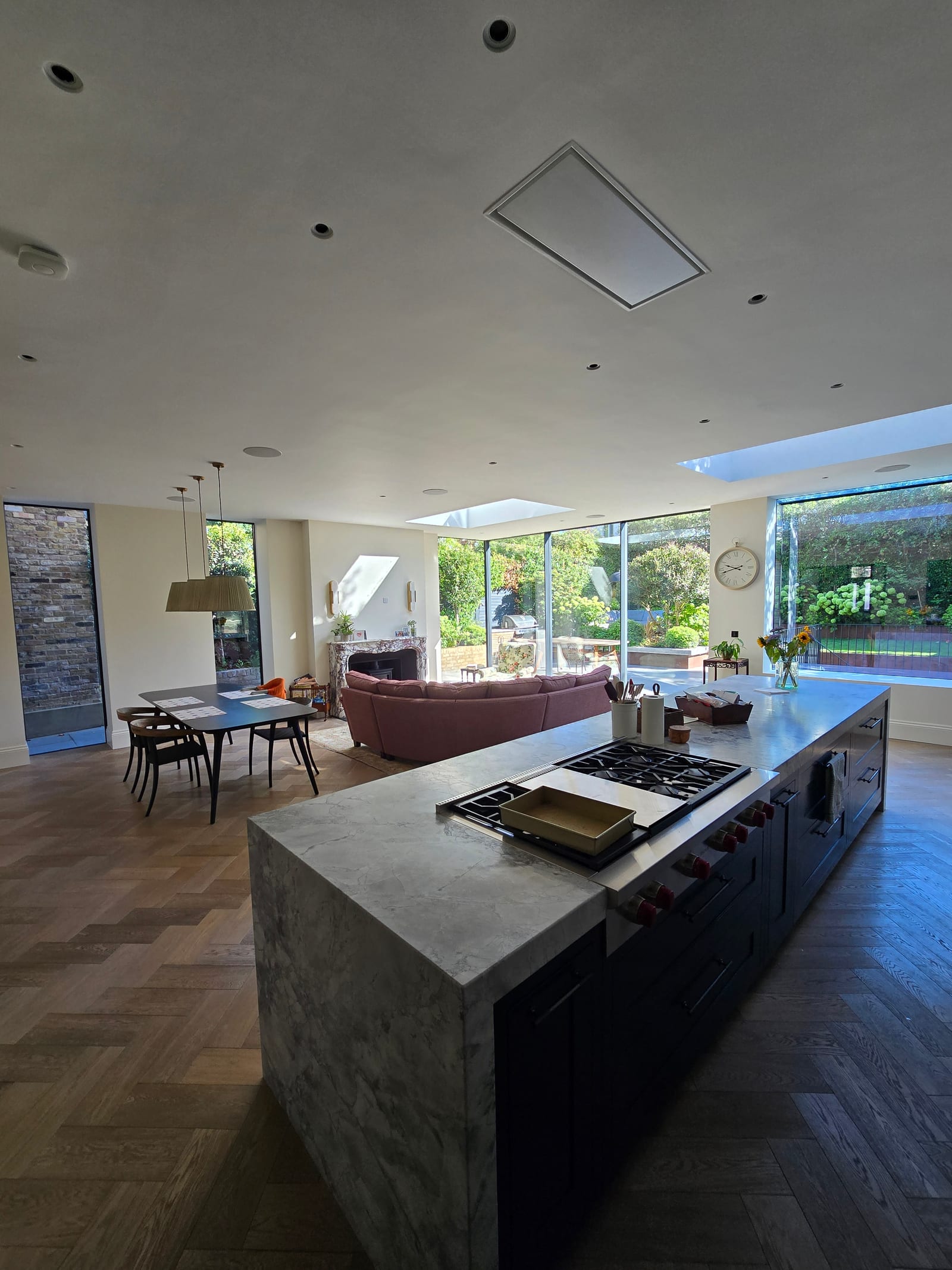 Open-plan kitchen and living space with cream walls, marble island, skylights, and garden glazing.