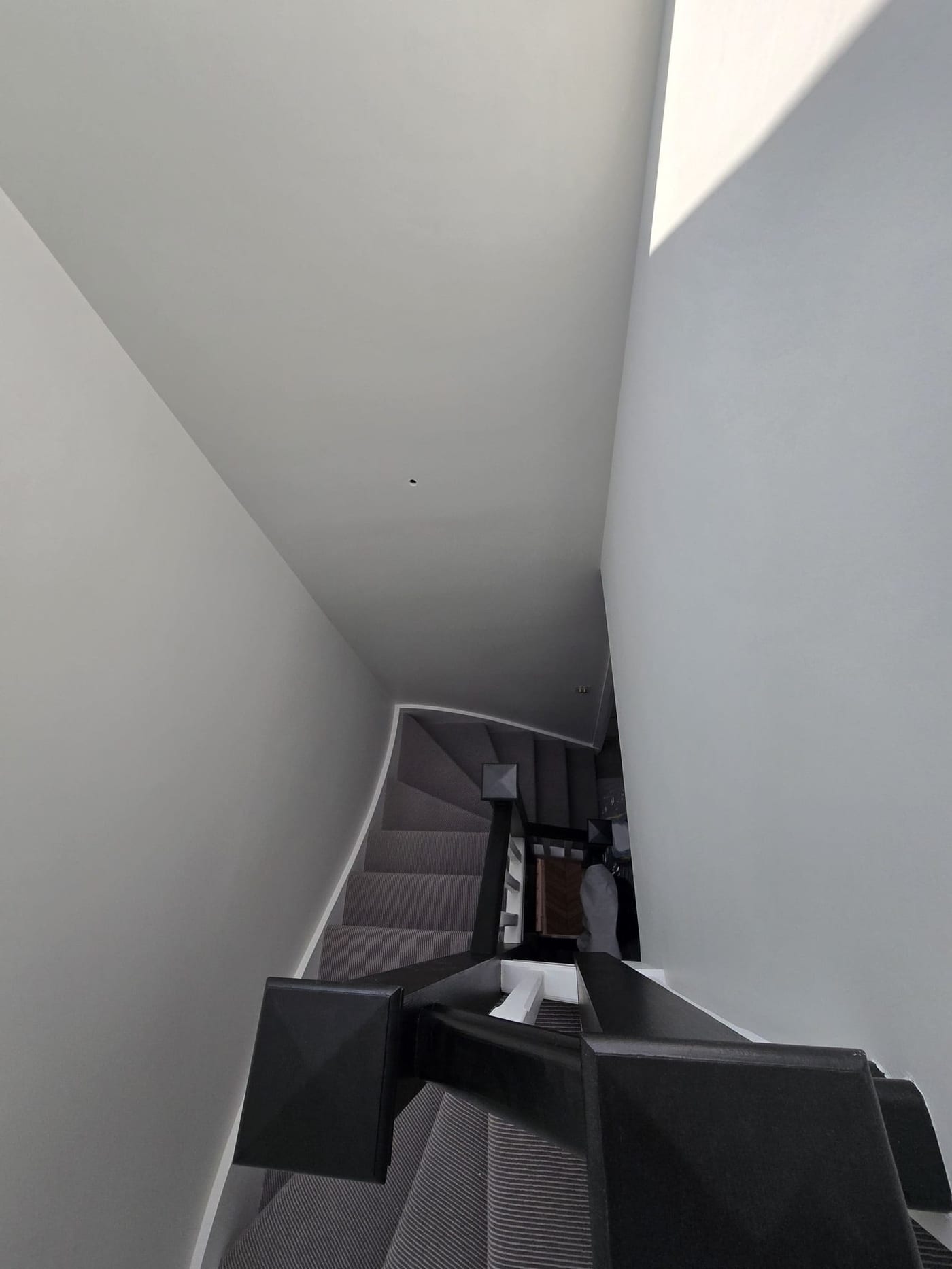 Narrow stairwell finished in a soft neutral paint with clean lines.